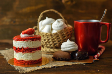 cake with strawberries, biscuits and a Red Cup of coffee on a wooden table