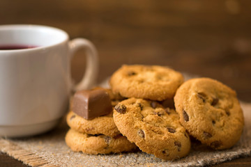 White cup of tea and cookies on dark wooden background
