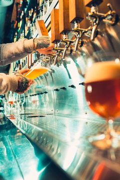 Hand of bartender pouring a large lager beer in tap.