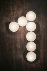 lit candles on a wooden background in the form of a number