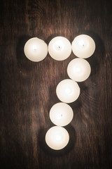 lit candles on a wooden background in the form of a number