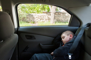 cute small boy sleeping on back seat of car