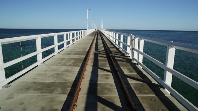 Perspective view of vintage rail track on jetty Busselton in Busselton town, Western Australia. Famous place at sunset light. Busselton jetty is the longest wooden pier in the world.