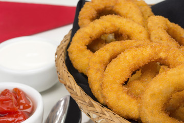 Onion rings in a basket in pub table on white background close