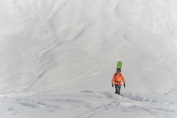 Snowboarder walking with a board behind his back