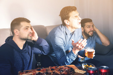 Males in suspense watching tv with beer and pizza
