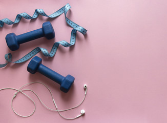 on a pink background dumbbells blue and flying centimeter figure sport headphones music soft light 