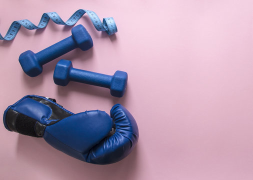 on a pink background dumbbells blue and flying centimeter figure sport boxing glove soft light 