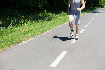 Young man jogging on treadmill in park, copy space