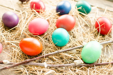 Fototapeta na wymiar Easter eggs and willow branch on old wooden boards and hay