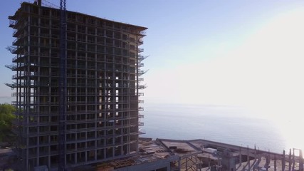 Building a modern tall skyscraper at coastline sunset drone footage