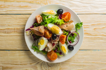 Fresh salad with mixed greens and cherry tomato in bowl on wooden background