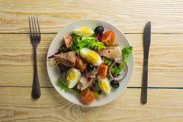 Fresh salad with mixed greens and cherry tomato in bowl on wooden background