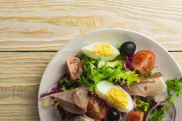 Fresh salad with mixed greens and cherry tomato in bowl on wooden background