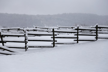 Fresh snow filled corral fences at rural winter snowy horse farm