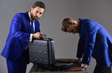 Businessmen with unhappy expression look into opened briefcase