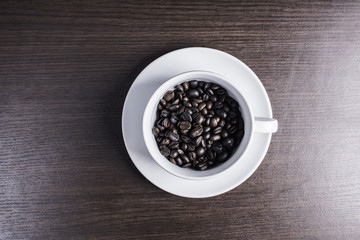 Coffee bean in white cup on wood background.