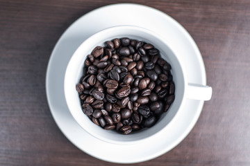 Coffee bean in white cup on wood background.
