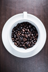Coffee bean in white cup on wood background.