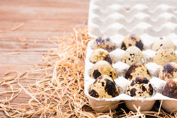 Quail eggs in a box and straw on a wooden table