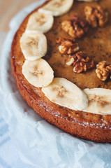 Close up of homemade cake with sliced banana and walnuts.