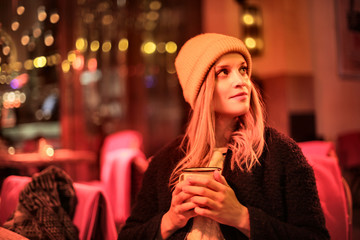 Cute girl sitting in a bar, drinking an hot chocolate