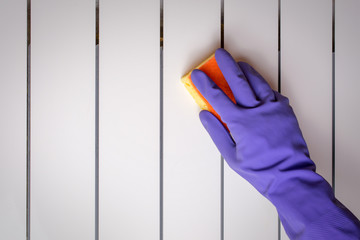 Hand blue glove wash radiator with yellow sponge. World Cleanup Day concept, copy space, close up,...