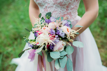 A bride in a white dress is holding a beautiful wedding bouquet.