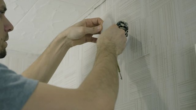 Man worker open the lid of electrical junction box and repairing the wires with screwdriver.