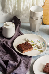 Millet brownie. White plates, cups of coffee and black esspreso maker. White and light blue background. Woolen tapestry.