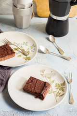 Millet brownie. White plates, cups of coffee and black esspreso maker. White and light blue background. Woolen tapestry.