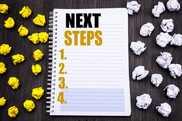 Conceptual hand writing text caption showing Next Steps. Business concept for Future Golas and Target Written on notepad note notebook book wooden background with sticky folded yellow and white