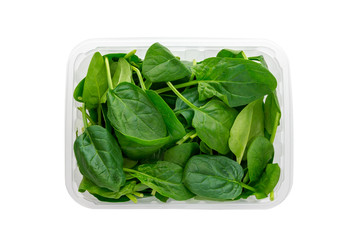 Green spinach in a plastic container. Spinach leaves in a container from a shop isolated on white background.