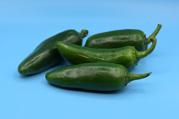 Fresh green jalapeno peppers arranged on a blue background. 