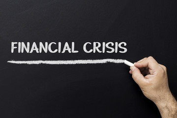 Hand writing Financial crisis on a chalkboard