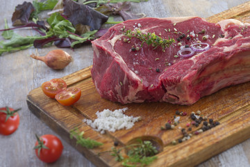Raw T-bone Steak for grill or BBQ on cutting board over on a aged wooden background, top view