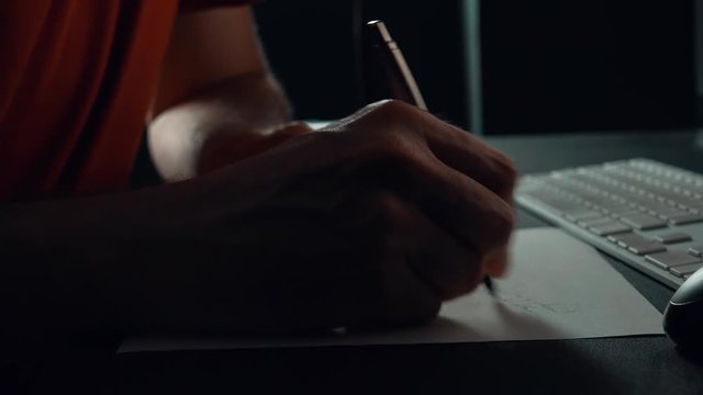 Close up of male hand writing notes in office t night, low key footage
