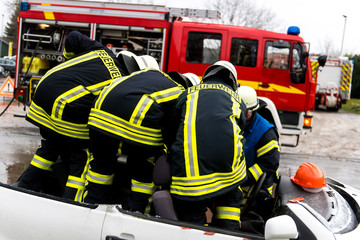 Naklejka premium Feuerwehrmänner befreien ein Unfallopfer nach einem Verkehrsunfall aus einem kaputten Auto
