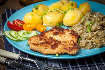 Fried pork chop, baked potatoes and fried young cabbage.