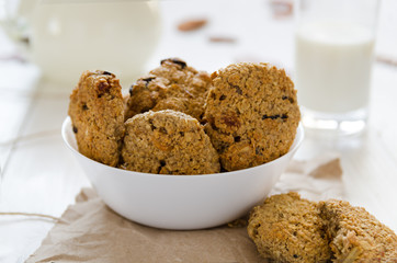 Homemade oatmeal cookies with raisins and prunes with jug and glass of milk on white wooden background. No sugar, no flour, no fast carbs. 
