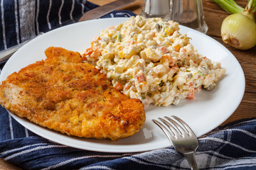 Fried pork chop in breadcrumbs, served with vegetable salad.