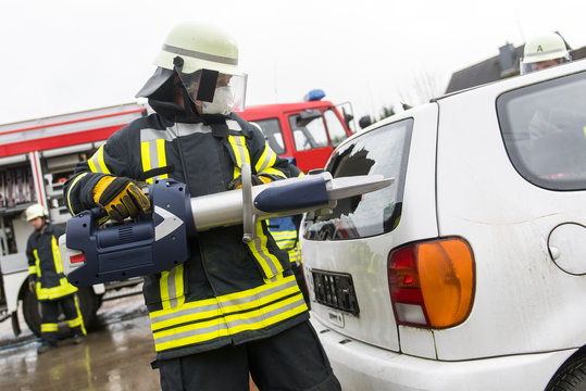 Feuerwehrm&auml;nner schneiden mit einer Rettungsschere ein Fahrzeug auf