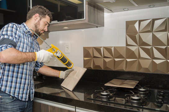 Man Renovating, Renovating The Kitchen, Installing Tile On The Wall.