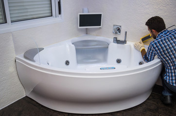 Installation of modern bath, (hot tub), applying sealant, bathtub with tv.