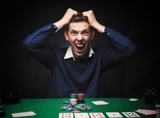 Man is playing poker. Emotional fail in game, game over for card player, man very angry with foolish choices, loosing all the chips on bank. Concept of victory and loosing