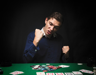Man is playing poker. Emotional  card player win in game, man very happy with making right choices, winning all the chips on bank. Concept of victory