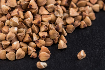 buckwheat groats on black background. Pile of buckwheat groats Close up