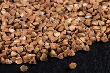 buckwheat groats on black background. Pile of buckwheat groats Close up