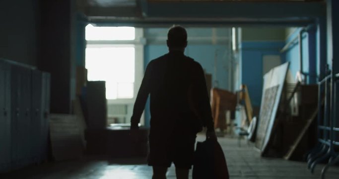 Tired athlete walking in the dark hall of the sports hall