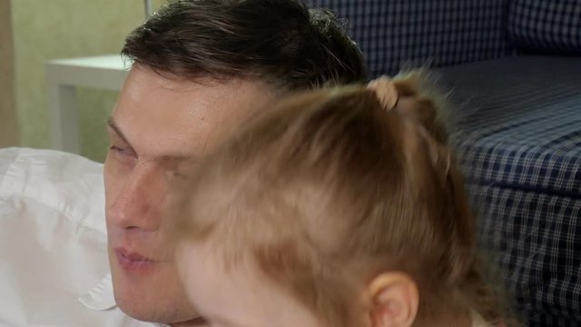 man and daughter watching television, sitting on the floor eating snacks